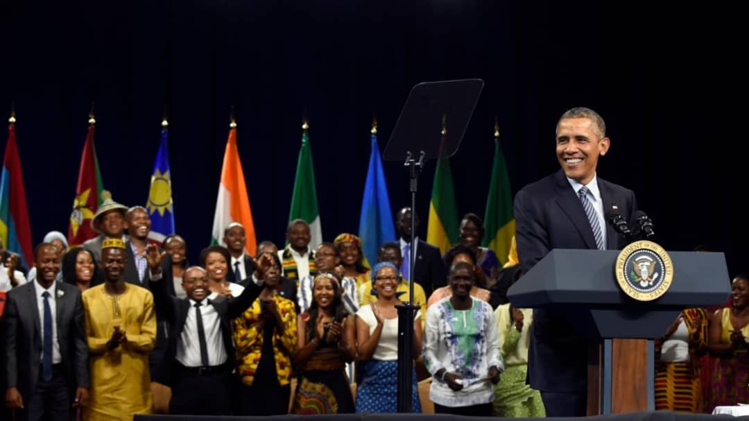 Fellowship participants gathered at an event with a speaker at a podium.